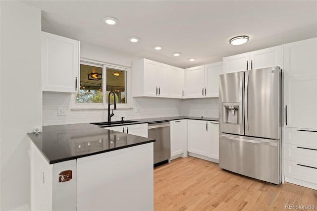 kitchen with kitchen peninsula, stainless steel appliances, white cabinetry, and sink