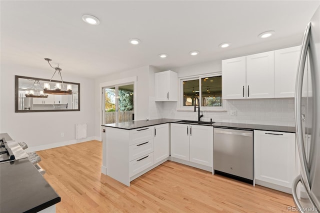 kitchen featuring appliances with stainless steel finishes, white cabinetry, pendant lighting, and sink