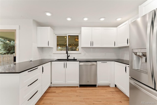 kitchen featuring sink, light hardwood / wood-style flooring, kitchen peninsula, white cabinets, and appliances with stainless steel finishes