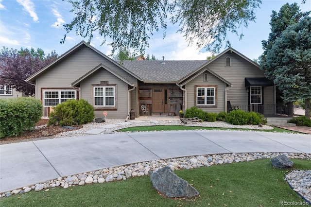 ranch-style house featuring a shingled roof and a front lawn