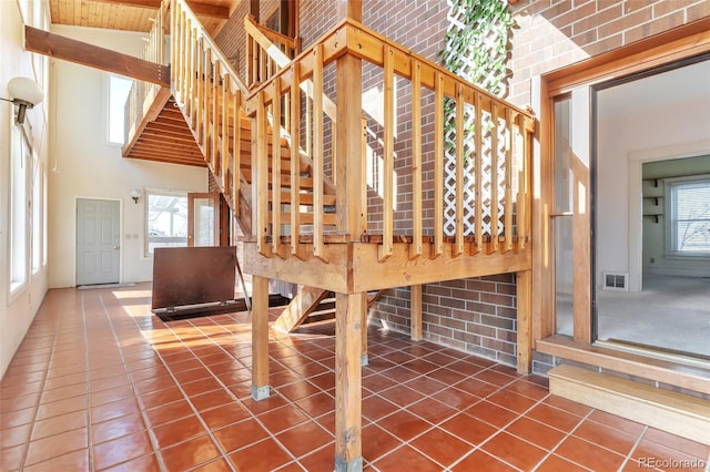 interior space featuring a towering ceiling, a healthy amount of sunlight, tile patterned flooring, and visible vents