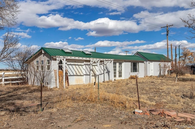 view of side of property featuring metal roof and fence