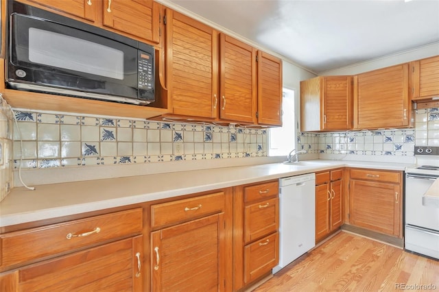 kitchen featuring light wood-style flooring, white appliances, a sink, light countertops, and tasteful backsplash