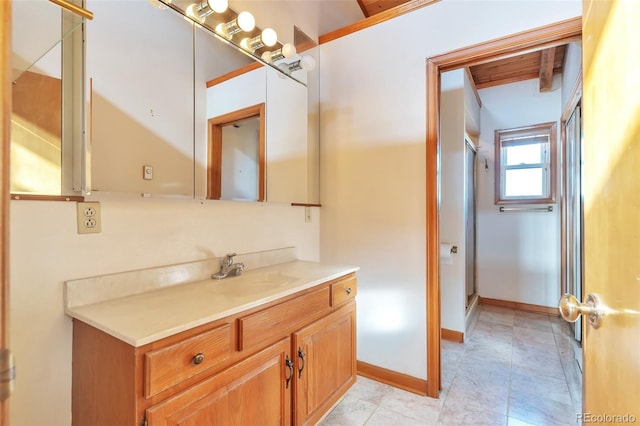 full bath with vanity, baseboards, and an enclosed shower