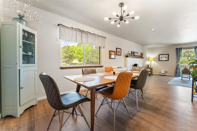 6170 Castlewood Ln, Colorado Springs, CO 80918 - dining room featuring a chandelier, wood finished floors, and a brick fireplace