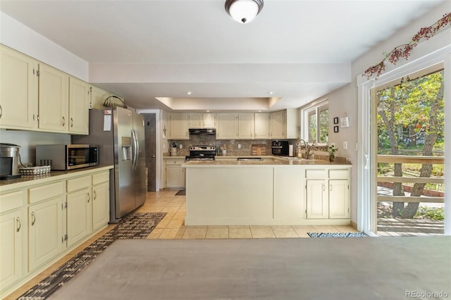 6170 Castlewood Ln, Colorado Springs, CO 80918 - kitchen featuring stainless steel appliances, cream cabinetry, a tray ceiling, a peninsula, and recessed lighting