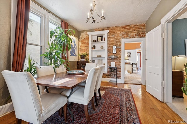 34 W Maple Ave, Denver, CO 80223 - dining room featuring a chandelier, light wood-type flooring, a textured ceiling, and brick wall