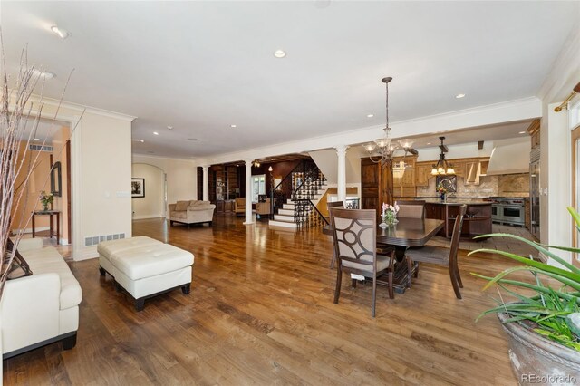 6901 E 12th Ave, Denver, CO 80220 - dining space with ornamental molding, a chandelier, arched walkways, stairs, and wood finished floors