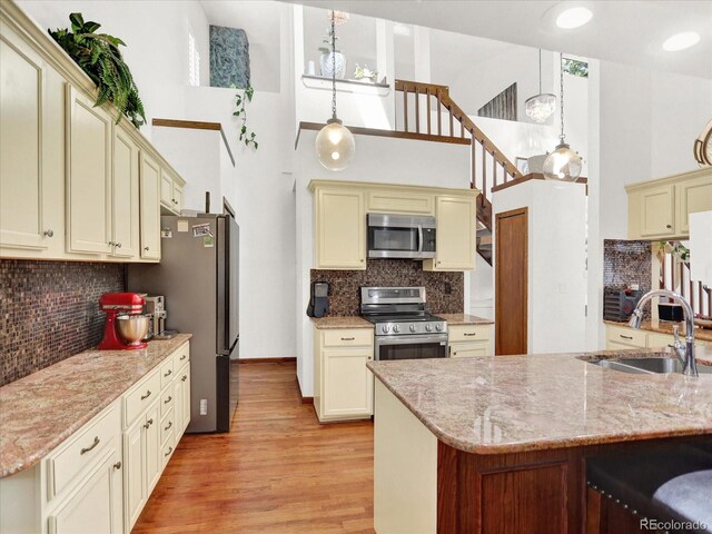 3596 S Telluride Way, Aurora, CO 80013 - kitchen with appliances with stainless steel finishes, cream cabinetry, a high ceiling, backsplash, and light wood-style flooring