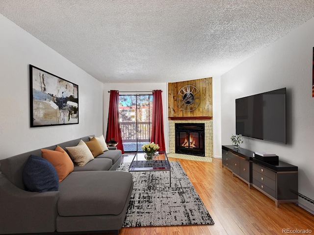 living room featuring light hardwood / wood-style floors, a textured ceiling, and a baseboard heating unit