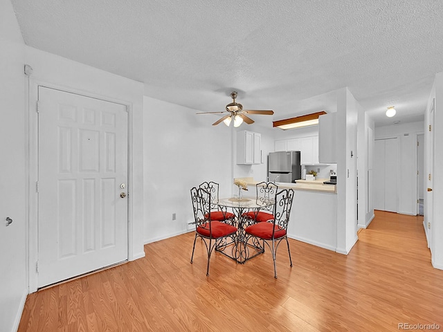 dining space featuring ceiling fan, light wood-type flooring, and a textured ceiling