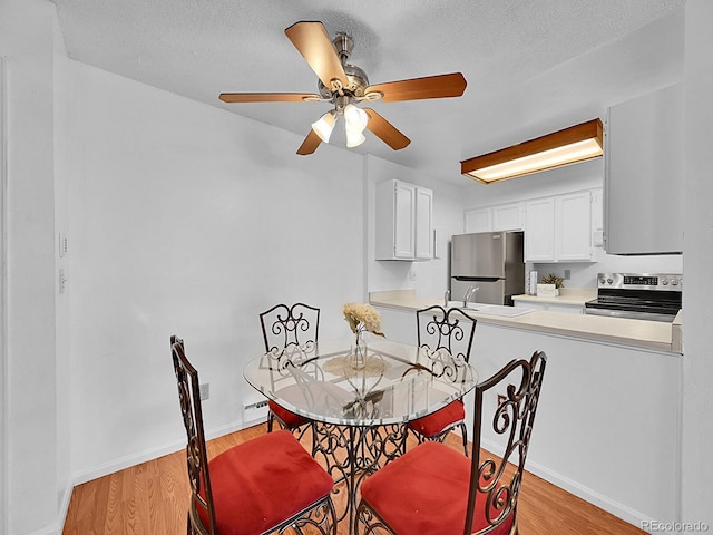 dining area featuring ceiling fan, light hardwood / wood-style flooring, and a textured ceiling