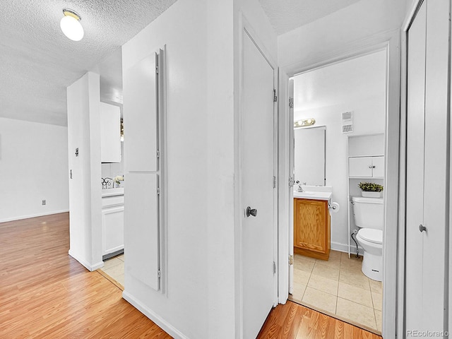 hallway featuring a textured ceiling and light hardwood / wood-style flooring