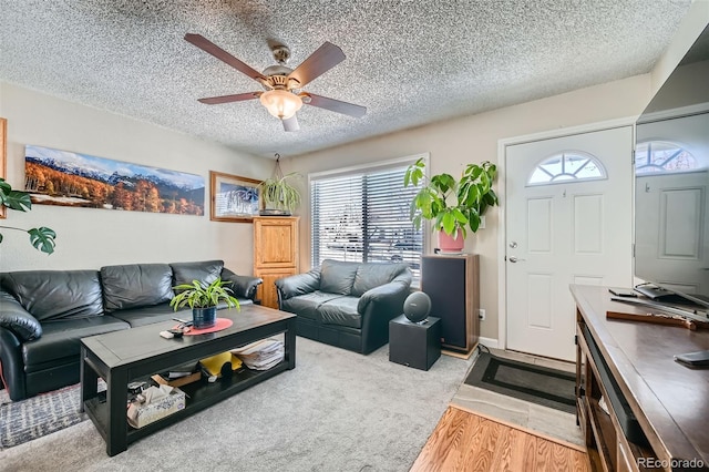 living room with ceiling fan, light wood-type flooring, and a textured ceiling