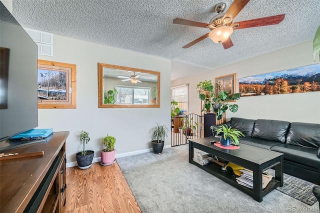 living room with ceiling fan, a textured ceiling, and light wood-type flooring