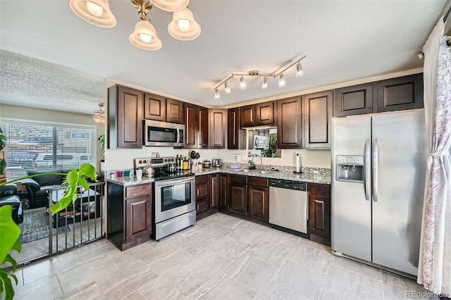 kitchen with dark brown cabinetry, light stone counters, and stainless steel appliances