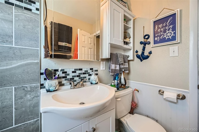 bathroom featuring vanity, toilet, and backsplash