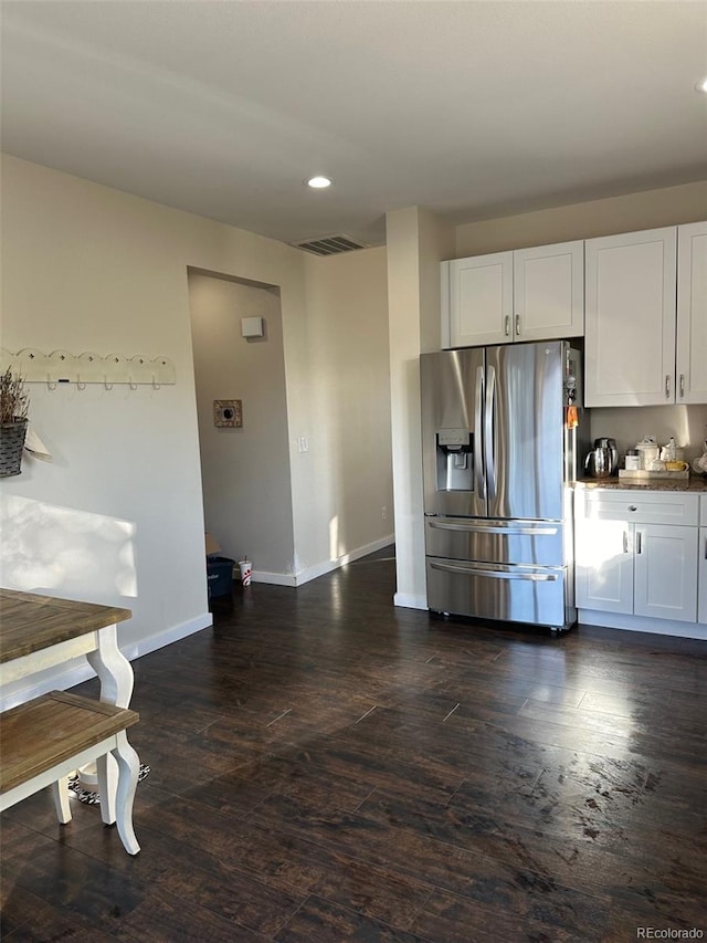 kitchen with stainless steel refrigerator with ice dispenser, dark hardwood / wood-style floors, and white cabinetry