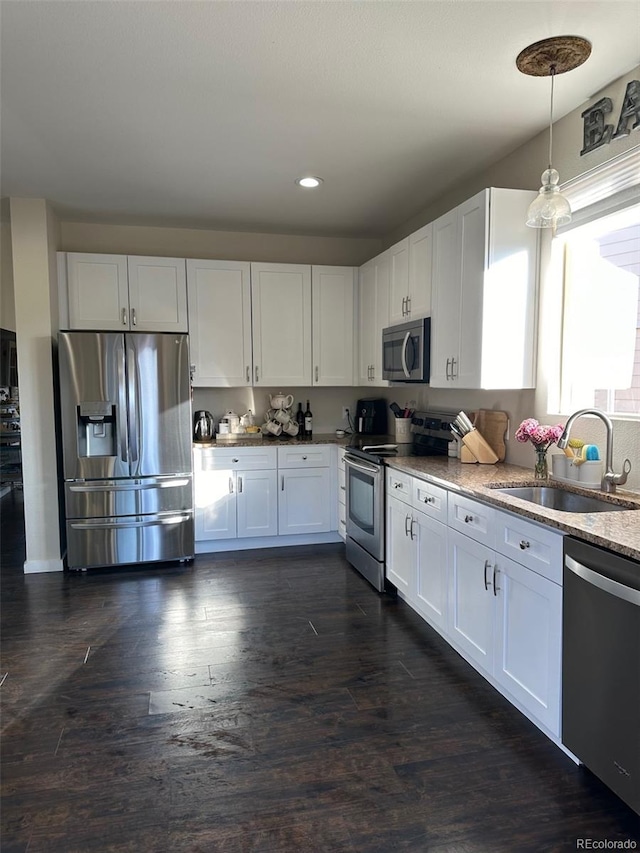 kitchen with white cabinets, hanging light fixtures, sink, dark wood-type flooring, and stainless steel appliances