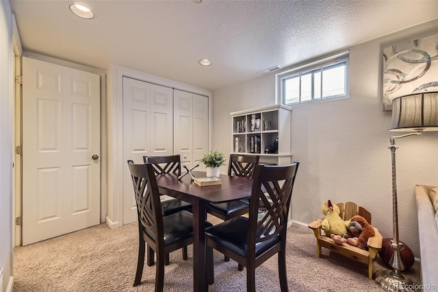 dining room with light carpet and a textured ceiling