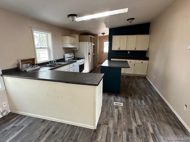 13193 E US Highway 160, Alamosa, CO 81101 - kitchen featuring white appliances, dark countertops, dark wood finished floors, and healthy amount of natural light