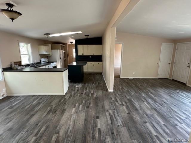 13193 E US Highway 160, Alamosa, CO 81101 - kitchen featuring freestanding refrigerator, dark countertops, dark wood-style flooring, open floor plan, and range