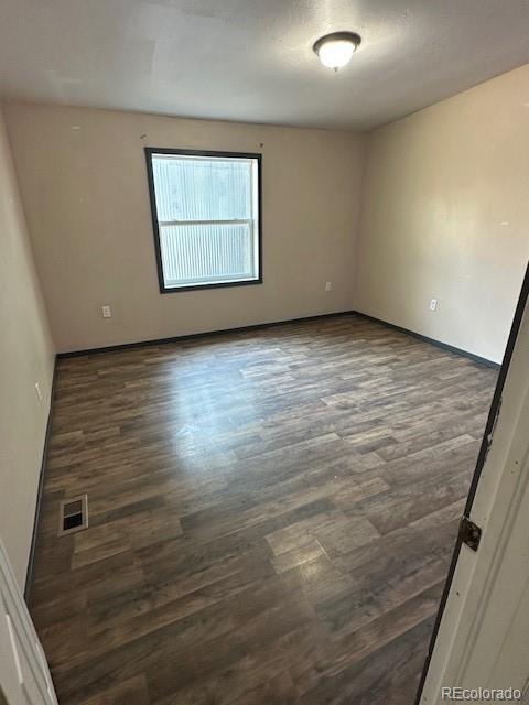 13193 E US Highway 160, Alamosa, CO 81101 - spare room featuring dark wood-type flooring and baseboards