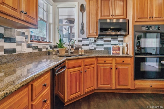 kitchen with backsplash, appliances with stainless steel finishes, stone countertops, sink, and dark hardwood / wood-style floors