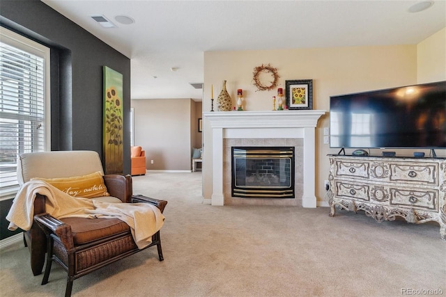 carpeted living room featuring a tile fireplace and a healthy amount of sunlight