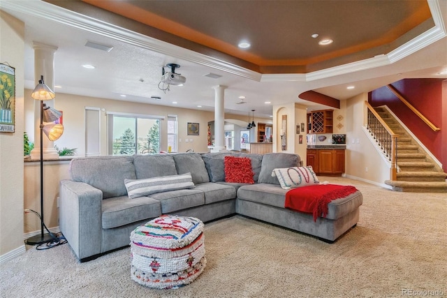 carpeted living room featuring ornamental molding, ornate columns, and a tray ceiling