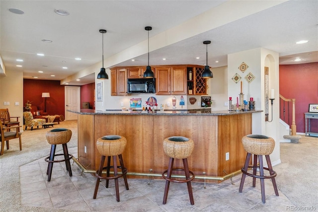 kitchen with a breakfast bar area, kitchen peninsula, and dark stone counters