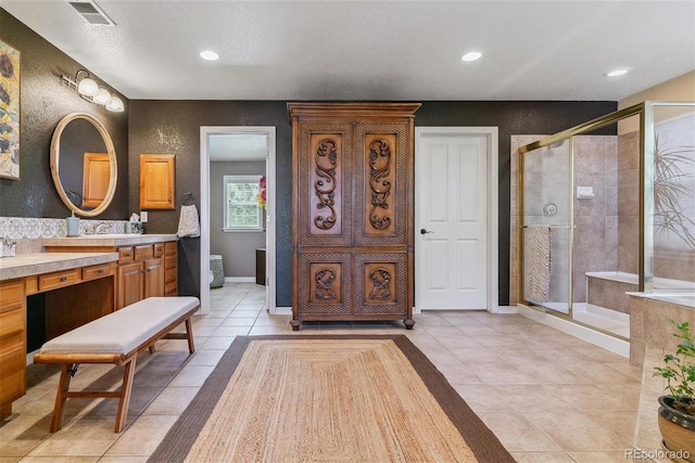 bathroom with tile patterned flooring, walk in shower, a textured ceiling, and vanity