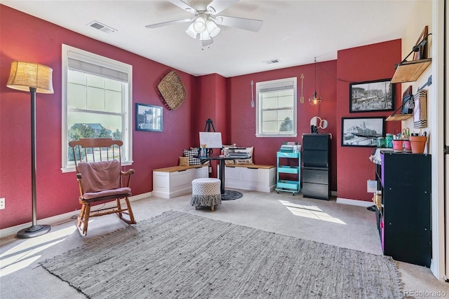 office space featuring a healthy amount of sunlight, ceiling fan, and light carpet