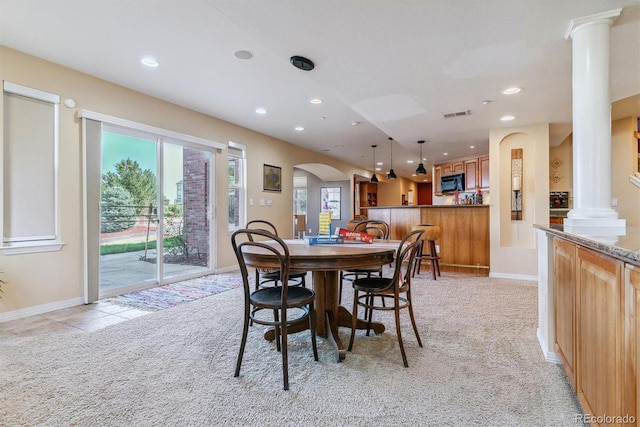 carpeted dining space featuring decorative columns