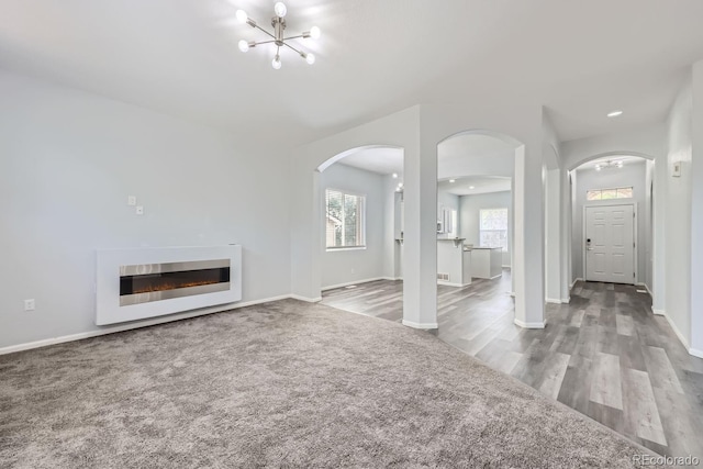 unfurnished living room featuring carpet and a chandelier