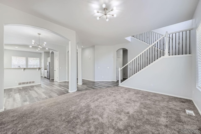 unfurnished living room with lofted ceiling, a chandelier, and carpet