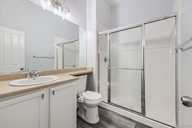 bathroom with walk in shower, vanity, toilet, and hardwood / wood-style floors