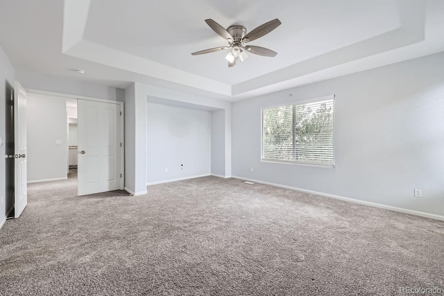 unfurnished bedroom featuring ceiling fan, a raised ceiling, and carpet floors