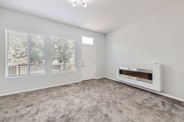 unfurnished living room featuring plenty of natural light and carpet