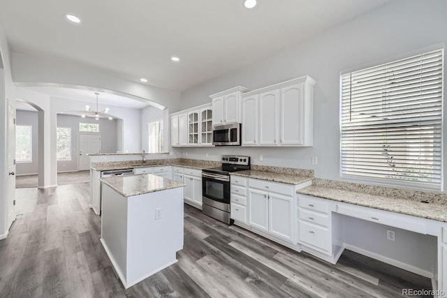 kitchen with white cabinetry, light stone counters, a center island, appliances with stainless steel finishes, and kitchen peninsula