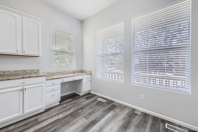 unfurnished office with dark hardwood / wood-style flooring and built in desk