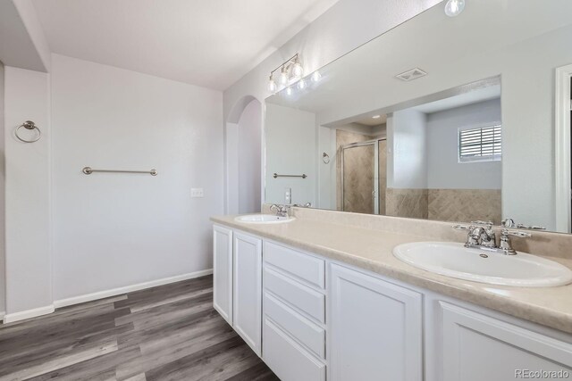 bathroom with hardwood / wood-style flooring, vanity, and a shower with door