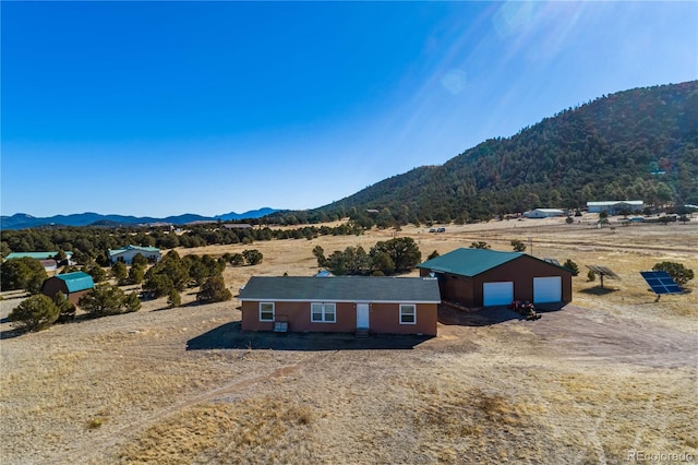 exterior space with a rural view, a mountain view, an outdoor structure, and a garage