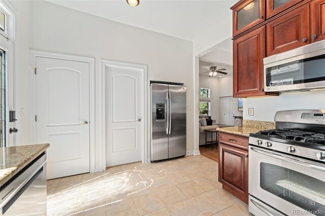 2829 N Franklin St, Denver, CO 80205 - kitchen with appliances with stainless steel finishes, light stone countertops, ceiling fan, glass insert cabinets, and light tile patterned flooring