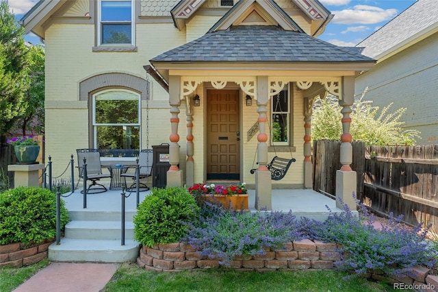 2829 N Franklin St, Denver, CO 80205 - doorway to property featuring covered porch, a shingled roof, and brick siding
