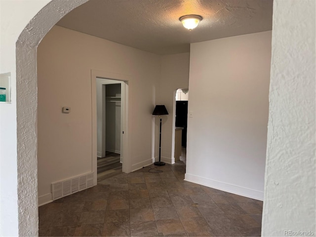 4807 Clayton St, Denver, CO 80216 - spare room featuring arched walkways, a textured ceiling, and dark stone finish floors