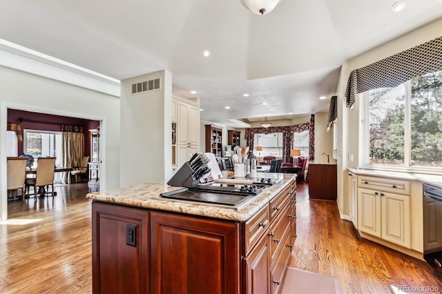 kitchen featuring visible vents, cream cabinets, light wood finished floors, black electric cooktop, and light stone countertops