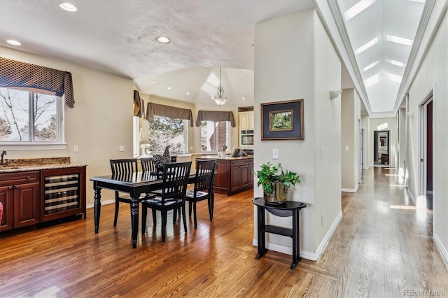 dining space featuring recessed lighting, baseboards, wine cooler, and wood finished floors