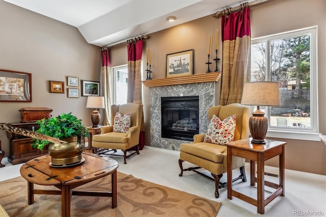 sitting room featuring carpet flooring, vaulted ceiling, plenty of natural light, and a high end fireplace