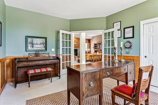 office space featuring french doors, a fireplace, and wainscoting